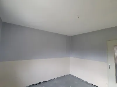 Pièce rénovée avec murs peints en deux tons gris et blanc et plafond finalisé
