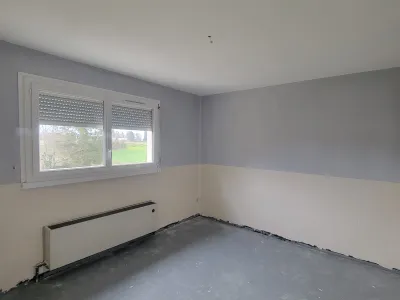 Pièce rénovée avec murs peints en deux tons gris et blanc, plafond blanc et fenêtre apportant de la lumière naturelle